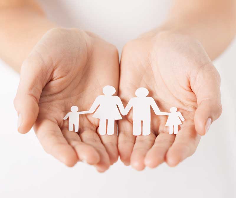 Hands holding paper cut out of a family
